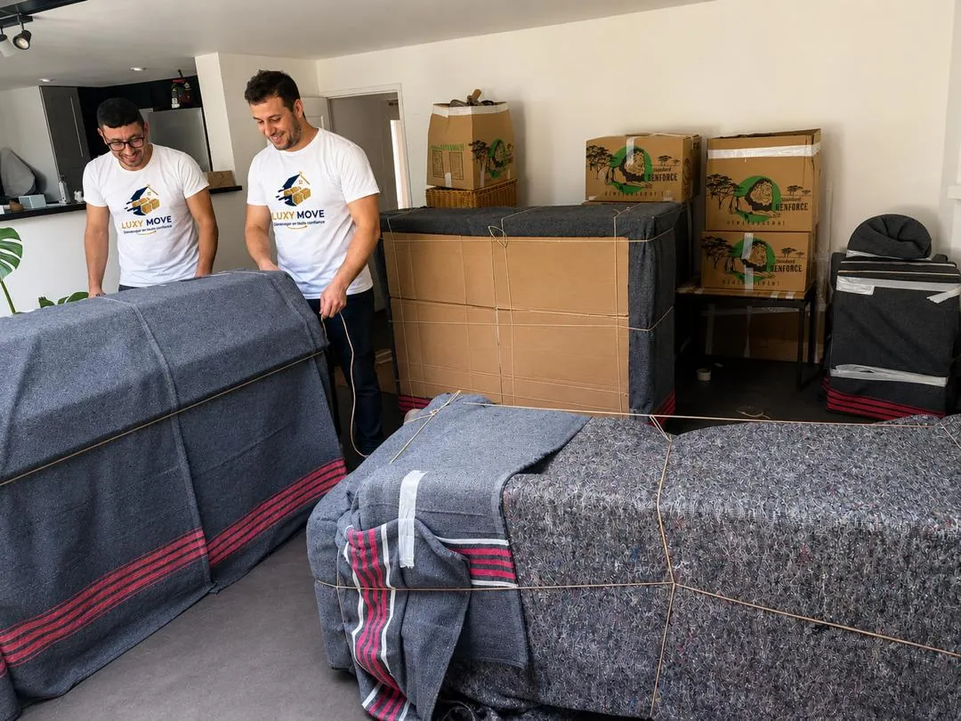 Déménageurs Luxy Move en uniforme préparant et emballant des cartons dans un appartement parisien
